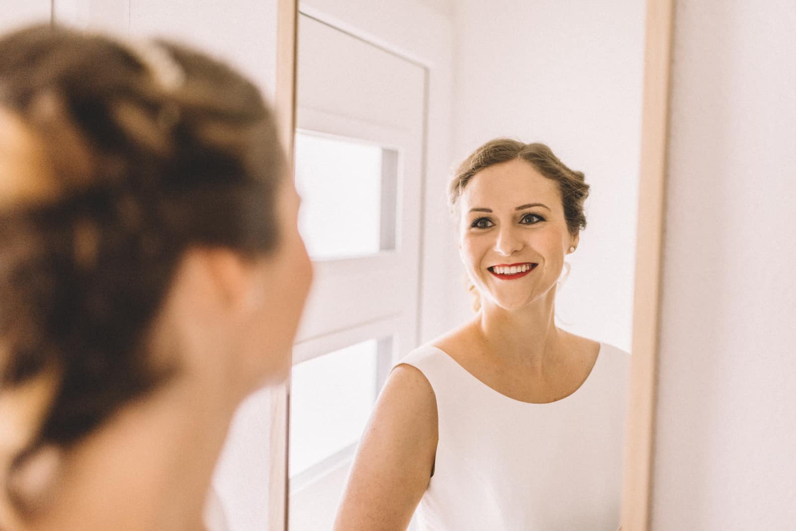 Braut lächelt in den Spiegel während der Hochzeitsfotografie in Beilstein, aufgenommen vom Hochzeitsfotografen Niklas Hesser.