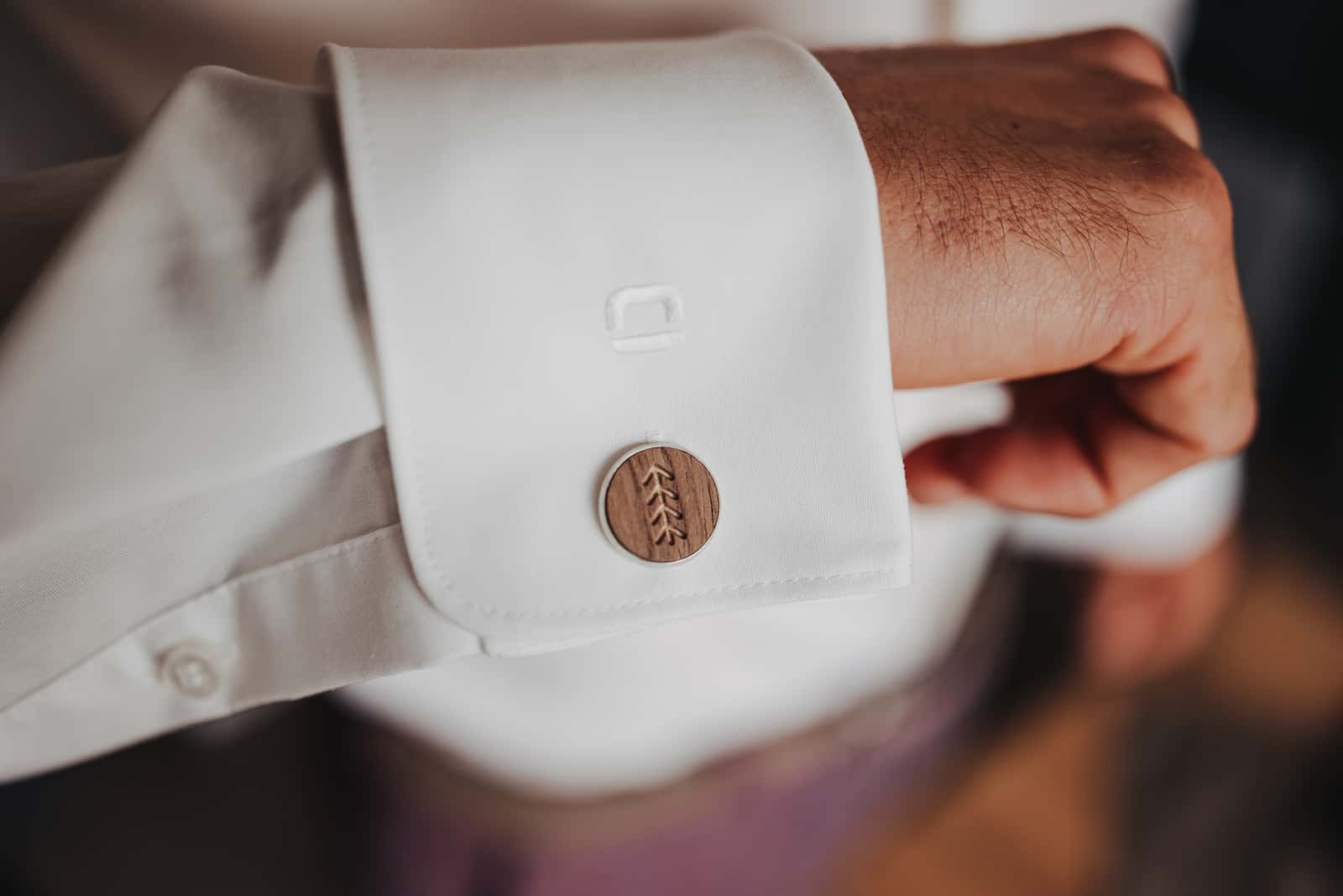 Detailaufnahme einer Manschette mit Holzknopf bei einer Hochzeit, fotografiert vom Hochzeitsfotografen in Heilbronn.