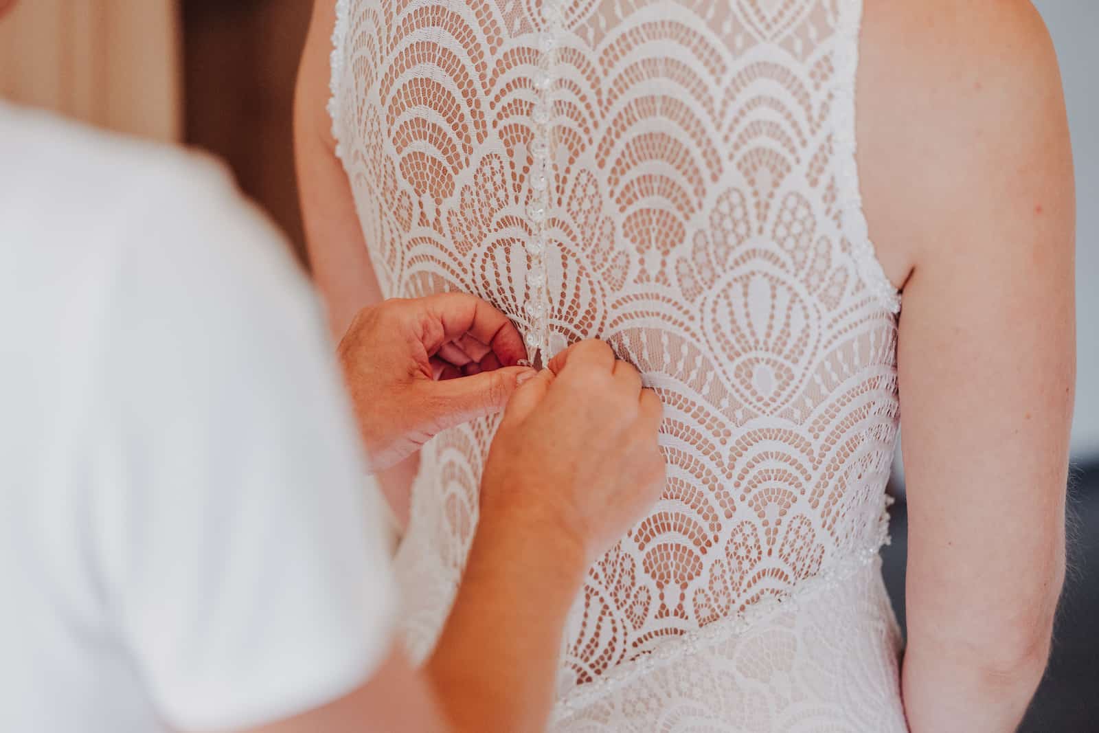Detailaufnahme einer Braut, die beim Ankleiden für die standesamtliche Hochzeit in Lohberg von einem Hochzeitsfotografen begleitet wird.