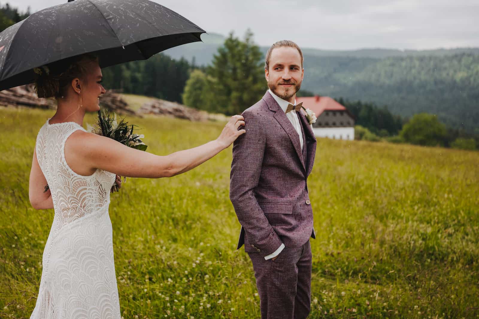 Hochzeitsfotografie im Freien bei Regen in Lohberg, Braut berührt Bräutigam unter einem Regenschirm.