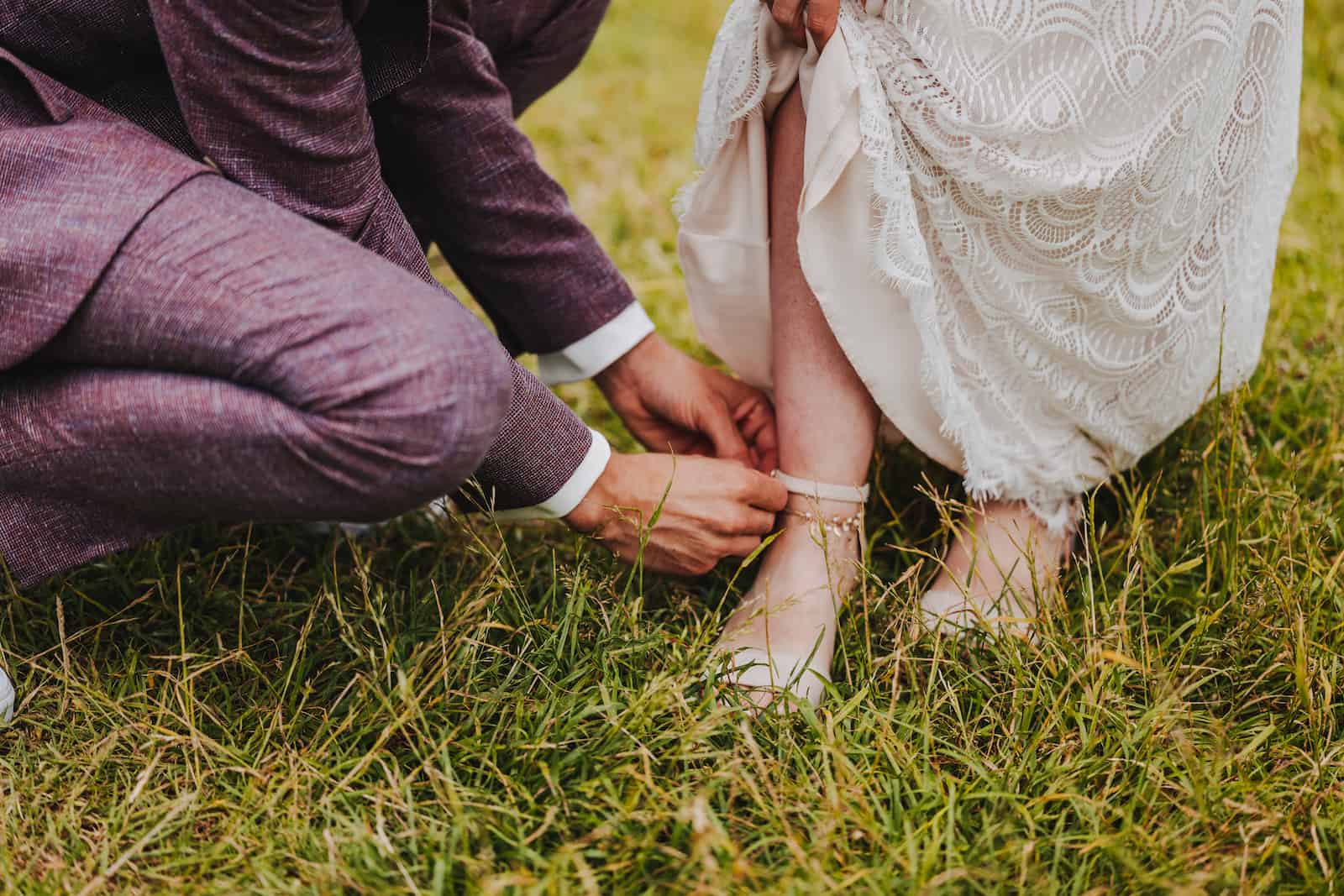 Detailaufnahme einer Hochzeitsszene in Lohberg, bei der ein Bräutigam der Braut den Schuh schließt, festgehalten vom Hochzeitsfotografen Niklas Hesser.