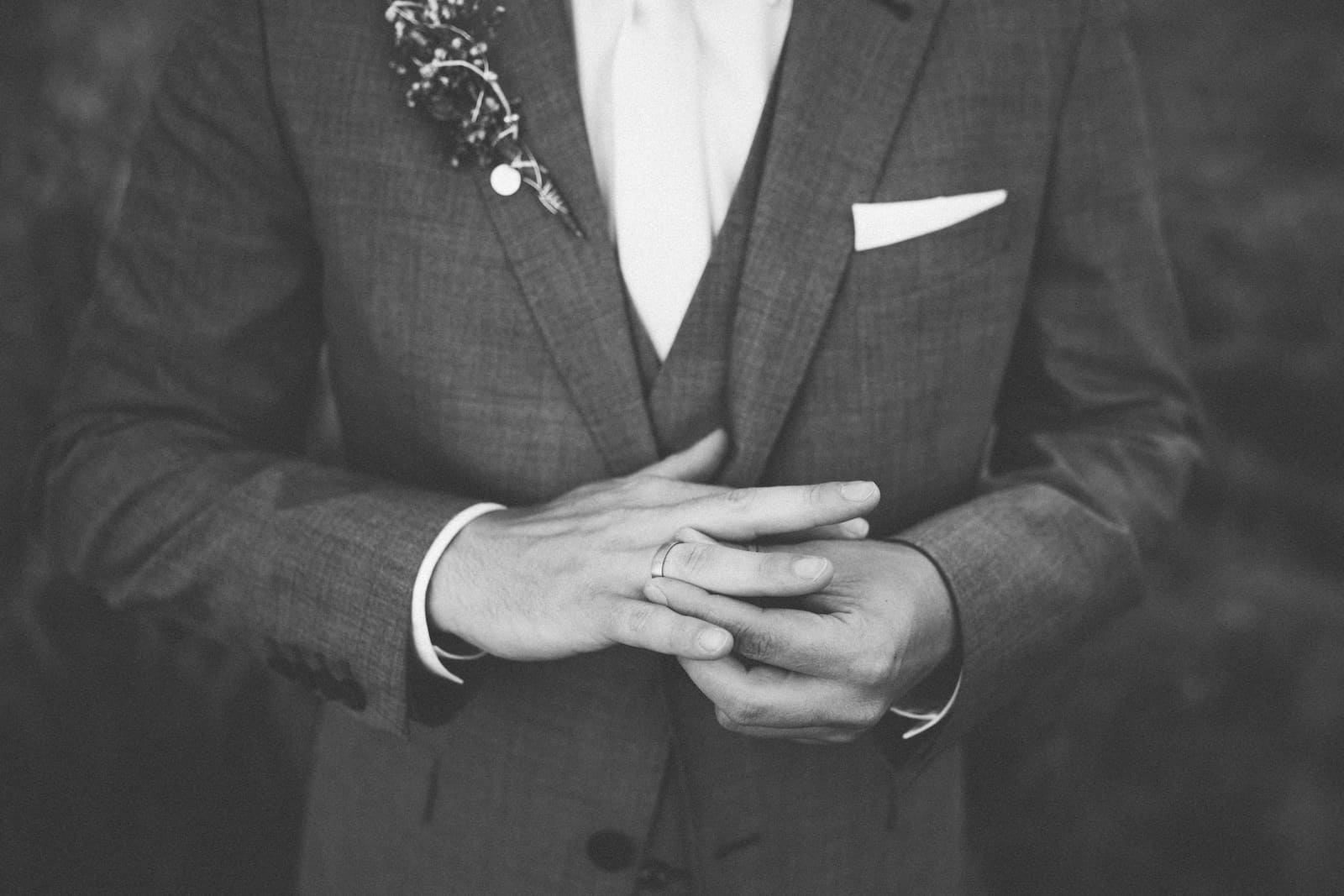 Detailaufnahme eines Bräutigams im Anzug, der seinen Ehering betrachtet, aufgenommen vom Hochzeitsfotografen in Möckmühl.