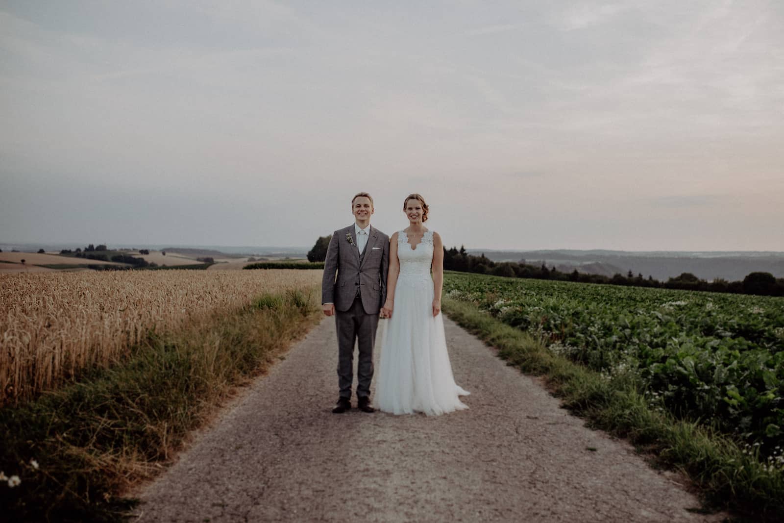 Hochzeitsfotografie in Möckmühl, Brautpaar auf Landstraße bei Sonnenuntergang