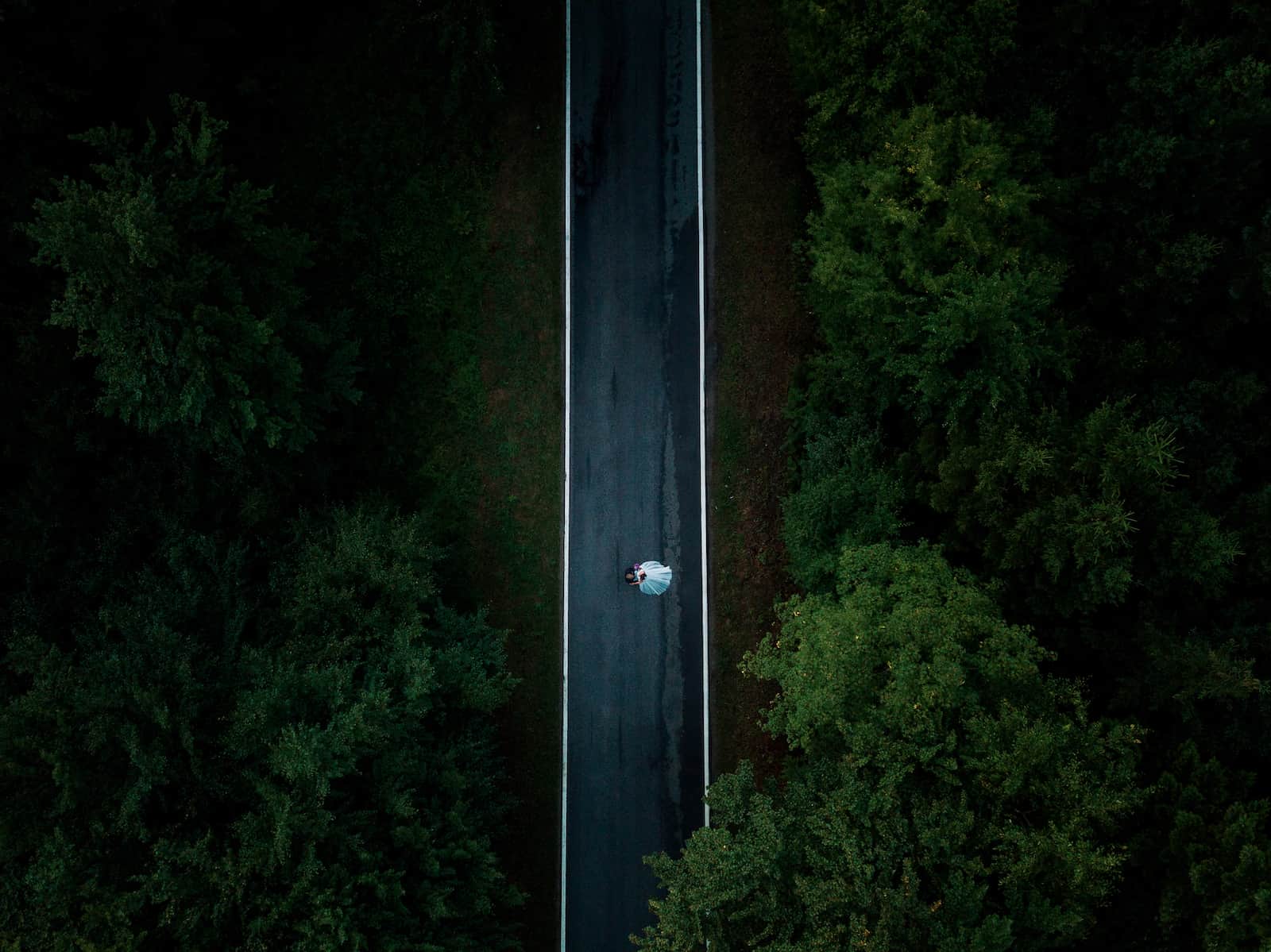 Luftaufnahme eines Brautpaares auf einer Straße in Wüstenrot, umgeben von Wald, aufgenommen vom Hochzeitsfotografen Niklas Hesser.