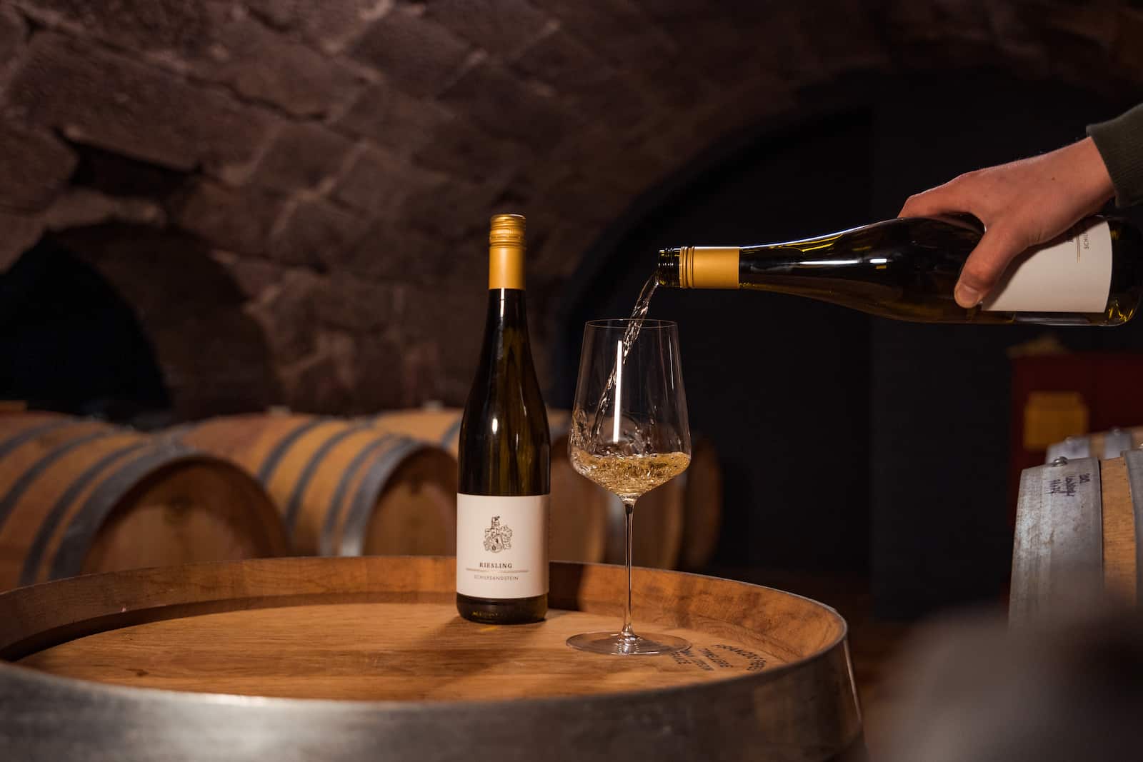 Unternehmensreportage in Erlenbach: Weinverkostung in einem Weinkeller mit Fokus auf eine Flasche Riesling und ein Glas, das vom Eventfotografen Niklas Hesser fotografiert wurde.