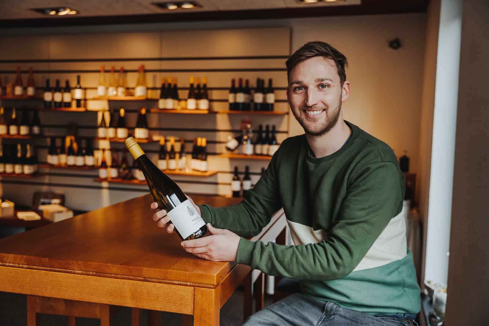 Unternehmensreportage in Erlenbach mit einem Mann, der eine Weinflasche präsentiert, fotografiert vom Eventfotografen Niklas Hesser.