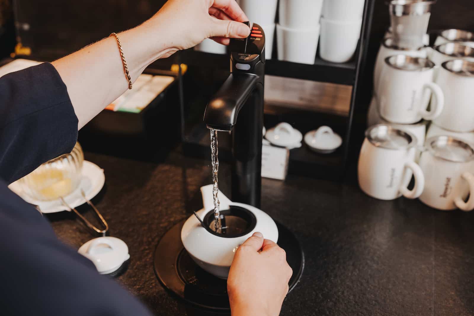 Businessfotografie in Heilbronn: Detailaufnahme einer Hand, die Wasser in eine Teekanne gießt.