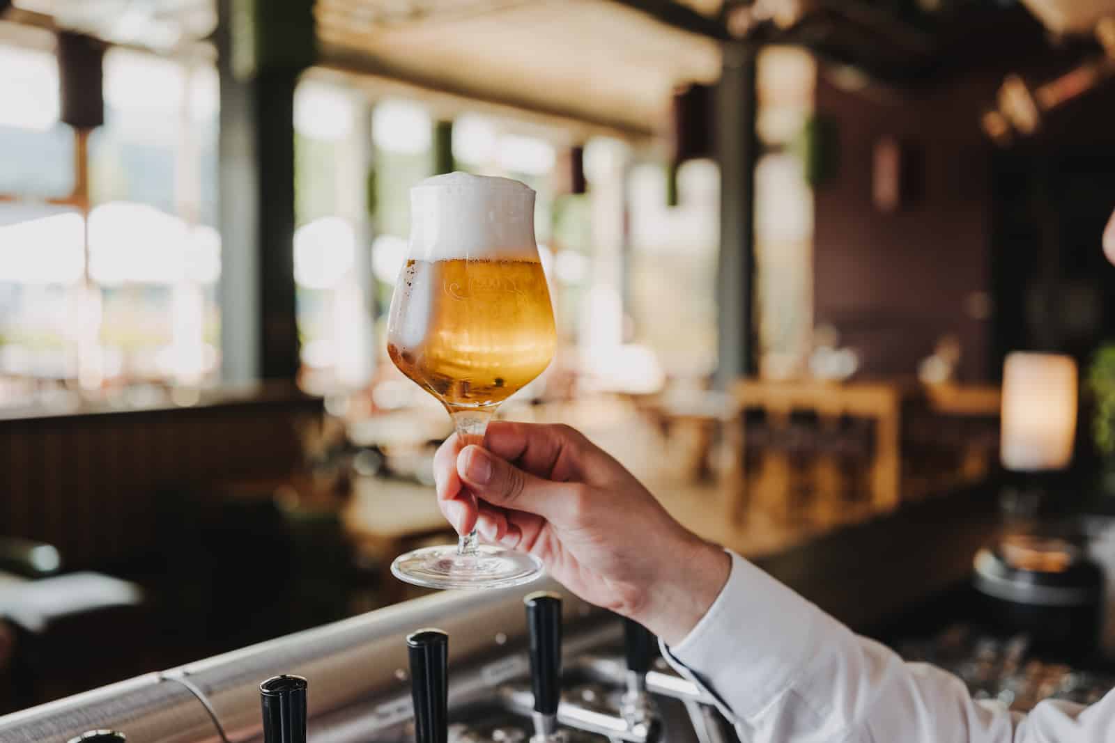 Businessfotografie in Heilbronn: Hand hält Bierglas in moderner Bar