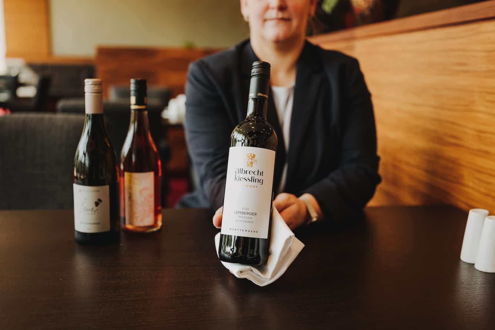 Businessfotografie in Heilbronn: Eine Person präsentiert eine Flasche Wein in einem eleganten Restaurant.