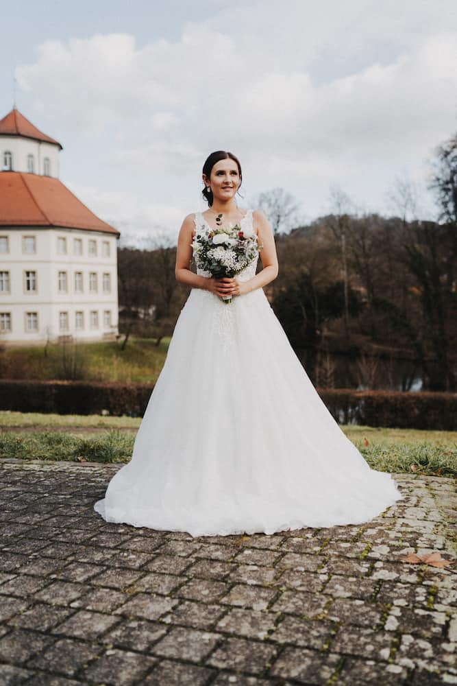 Braut im weißen Kleid vor einem Schloss in Backnang, aufgenommen vom Hochzeitsfotografen Niklas Hesser.