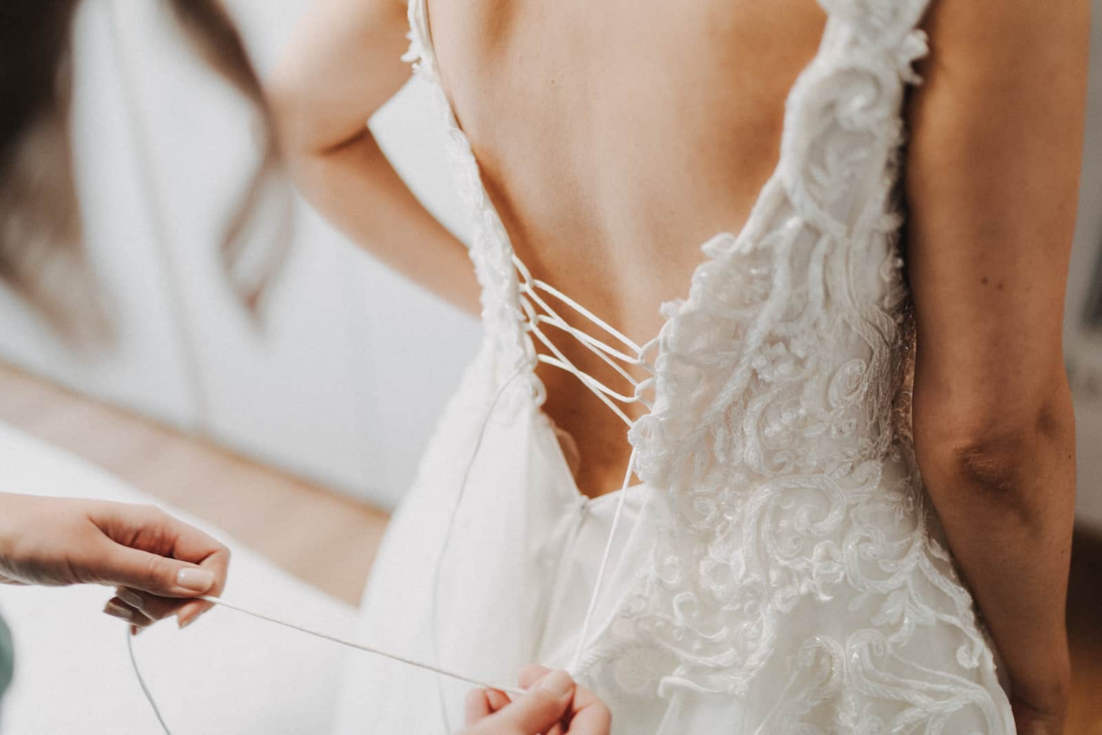Detailaufnahme einer Braut beim Schnüren des Hochzeitskleides, fotografiert vom Hochzeitsfotografen in Backnang.