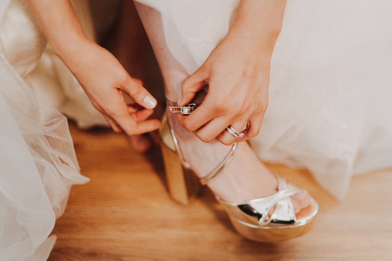 Detailaufnahme einer Braut, die ihre goldenen Hochzeitsschuhe anzieht, fotografiert vom Hochzeitsfotografen in Backnang.