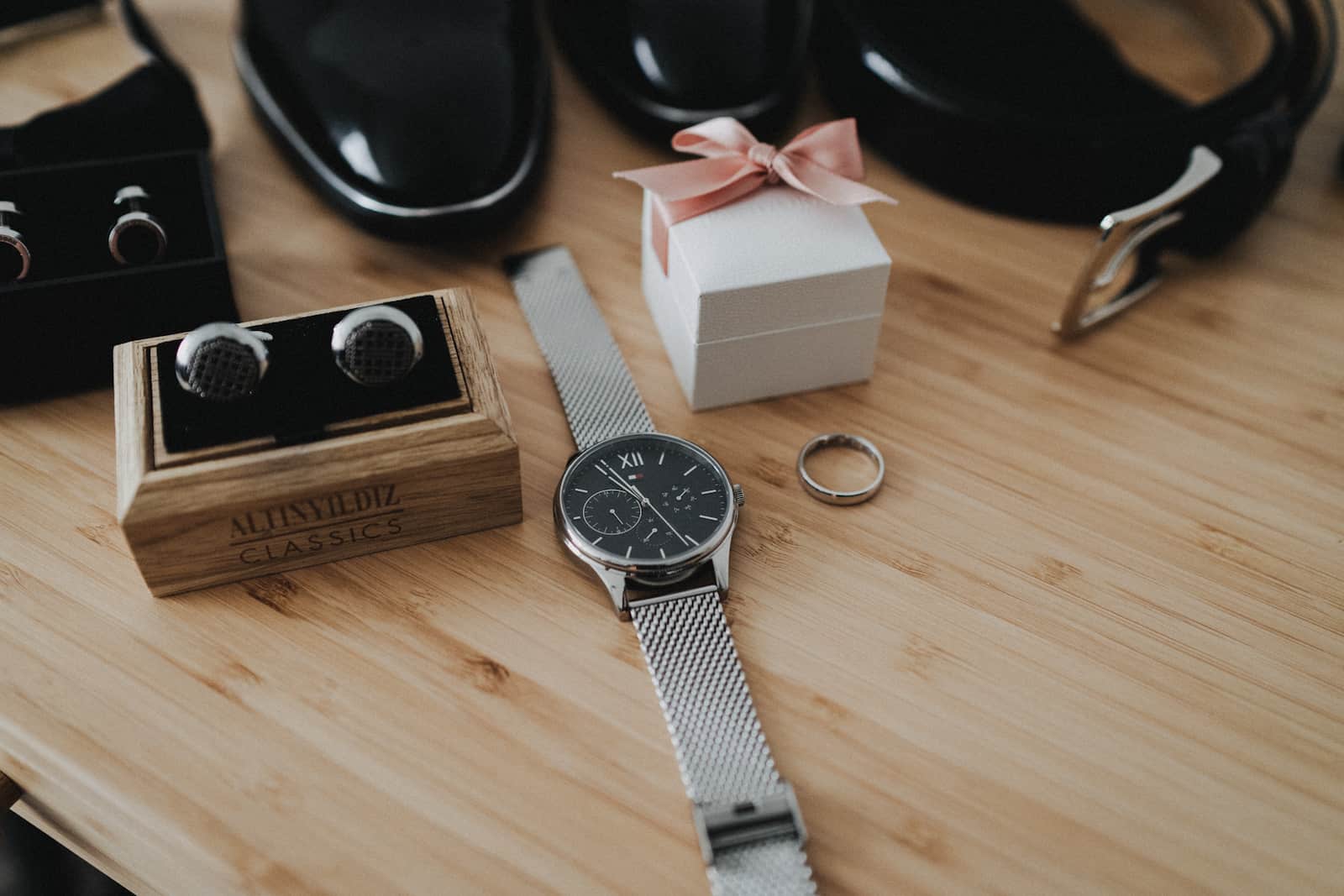 Detailaufnahme von Hochzeitsaccessoires, darunter eine Uhr, Manschettenknöpfe und ein Ehering, fotografiert vom Hochzeitsfotografen in Backnang.