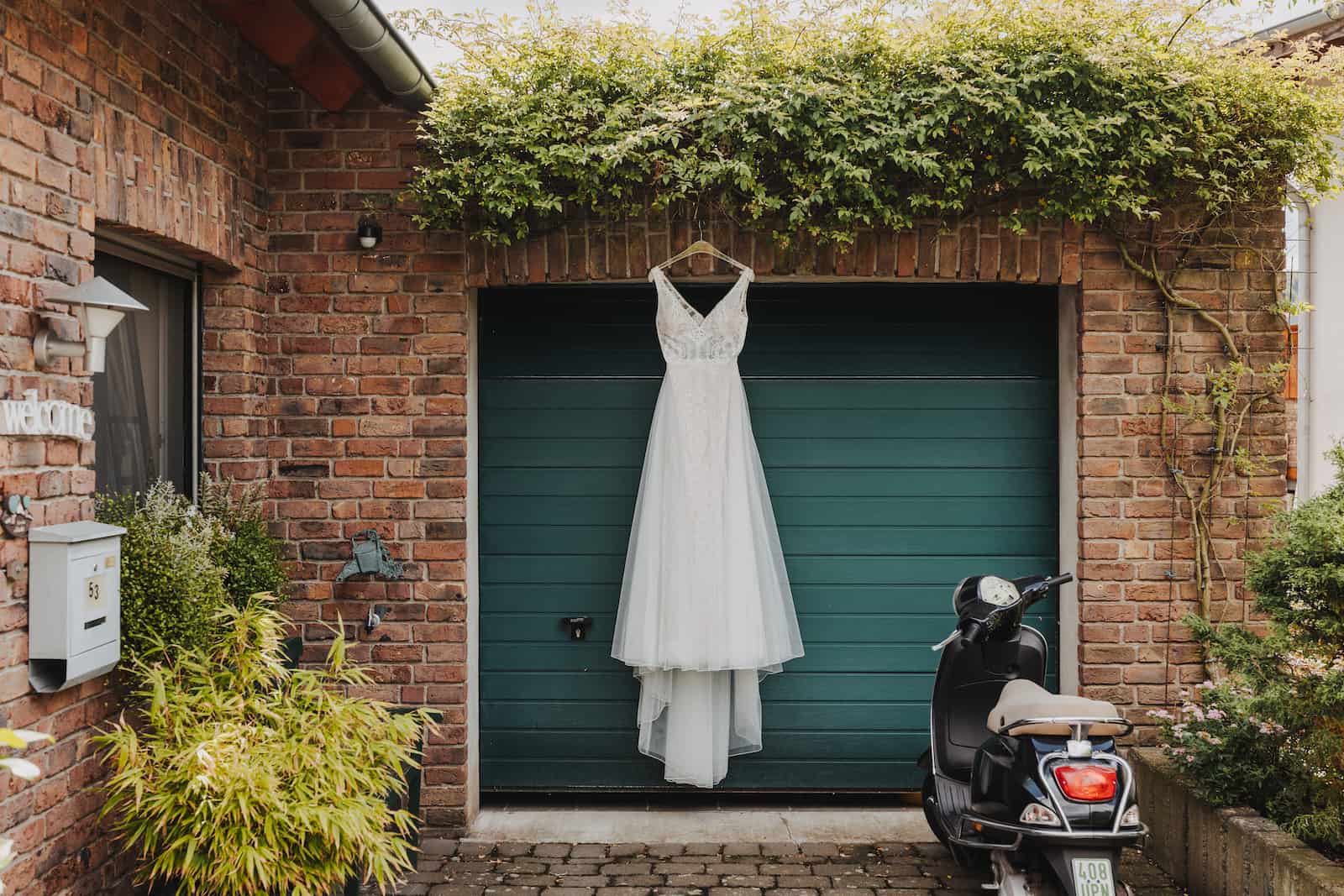 Hochzeitskleid hängt vor einer Garage in Heilbronn, fotografiert vom Hochzeitsfotografen Niklas Hesser.