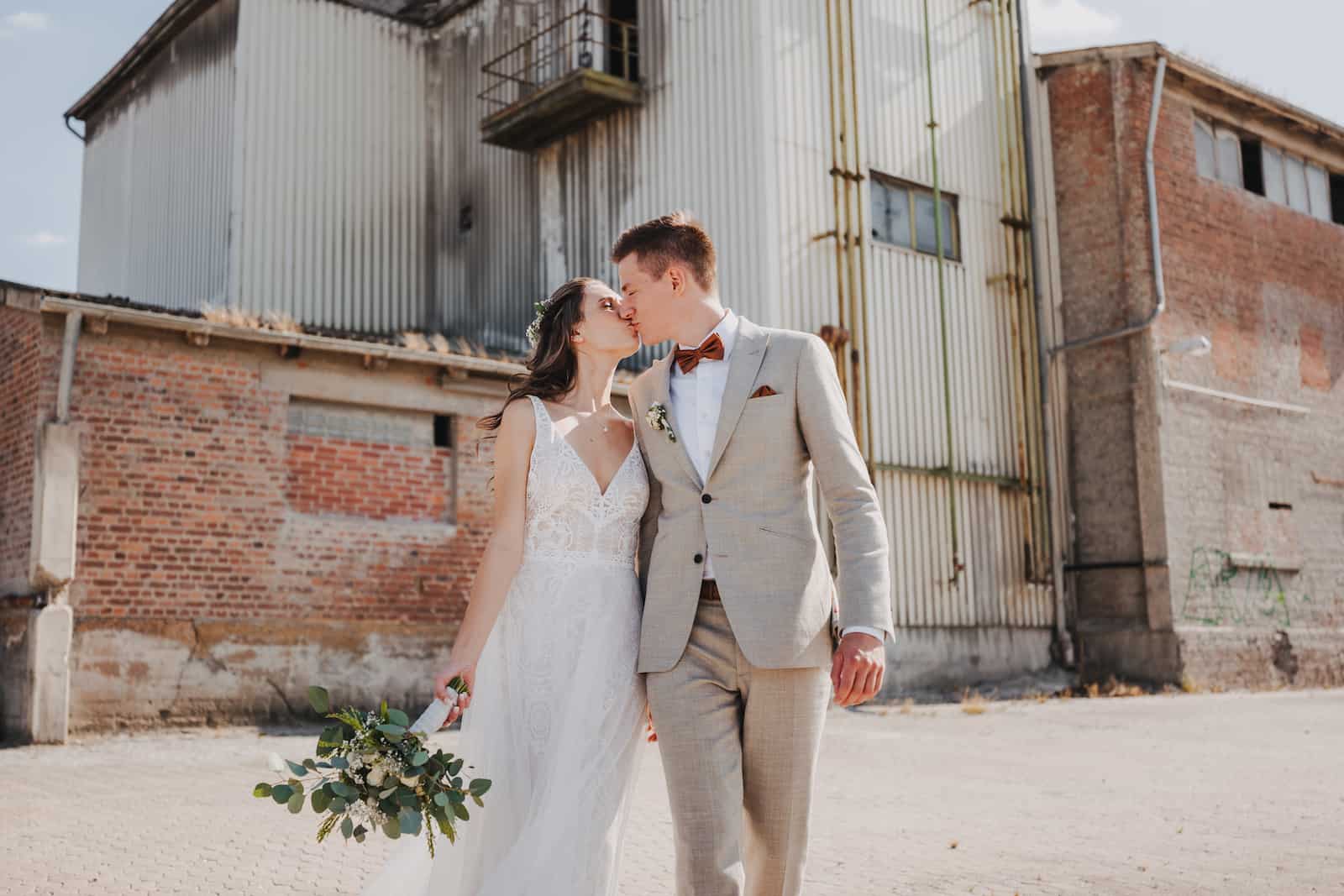 Hochzeitsfotografie in Heilbronn: Brautpaar Maike und Patrick bei einem romantischen Kuss vor einer industriellen Kulisse, aufgenommen vom Hochzeitsfotografen Niklas Hesser.