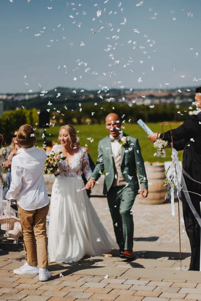 Hochzeitsfotografie in Kernen mit einem glücklichen Brautpaar unter Konfettiregen, aufgenommen vom Hochzeitsfotografen Niklas Hesser.