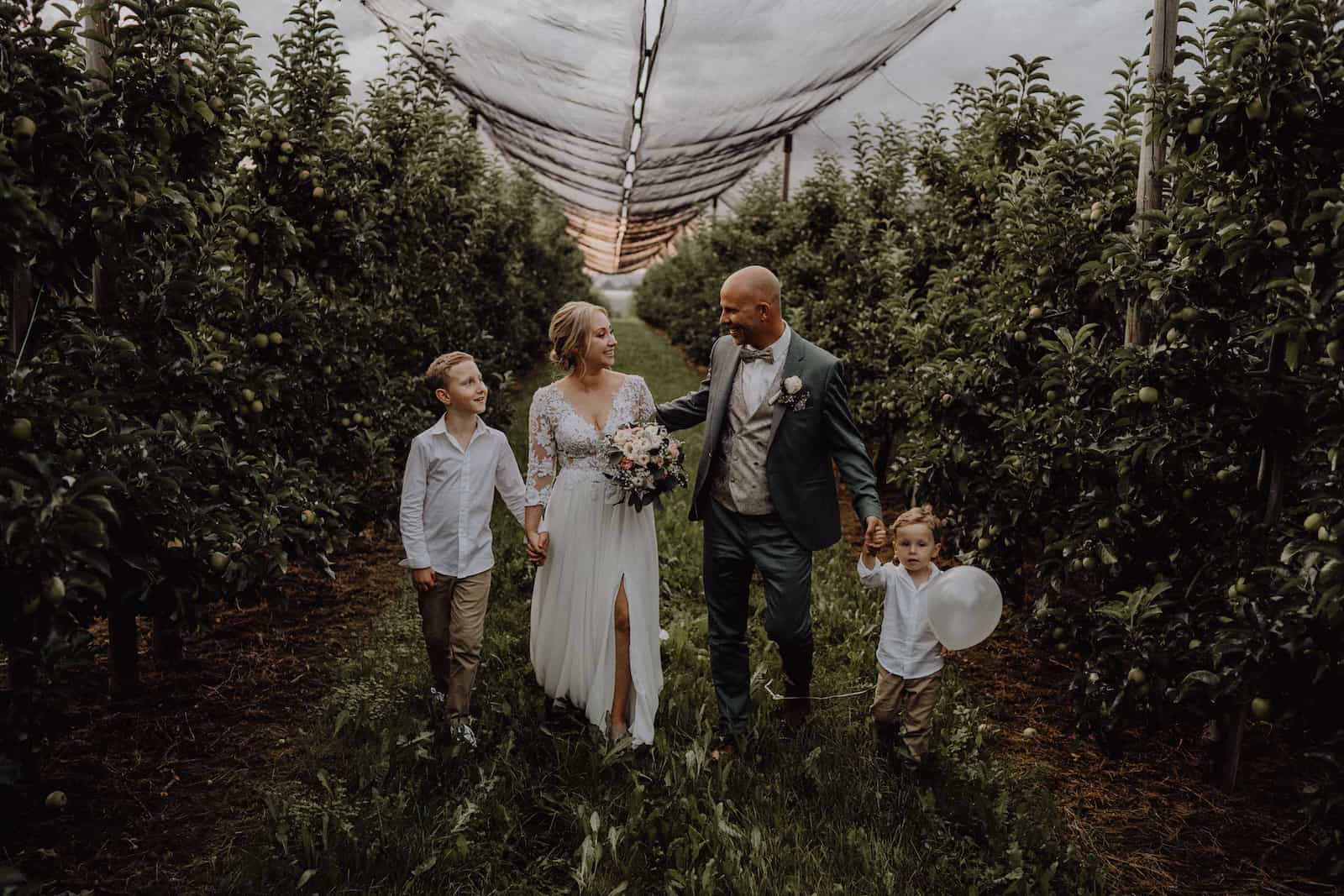 Hochzeitsfotografie in Kernen: Brautpaar mit Kindern im Obstgarten
