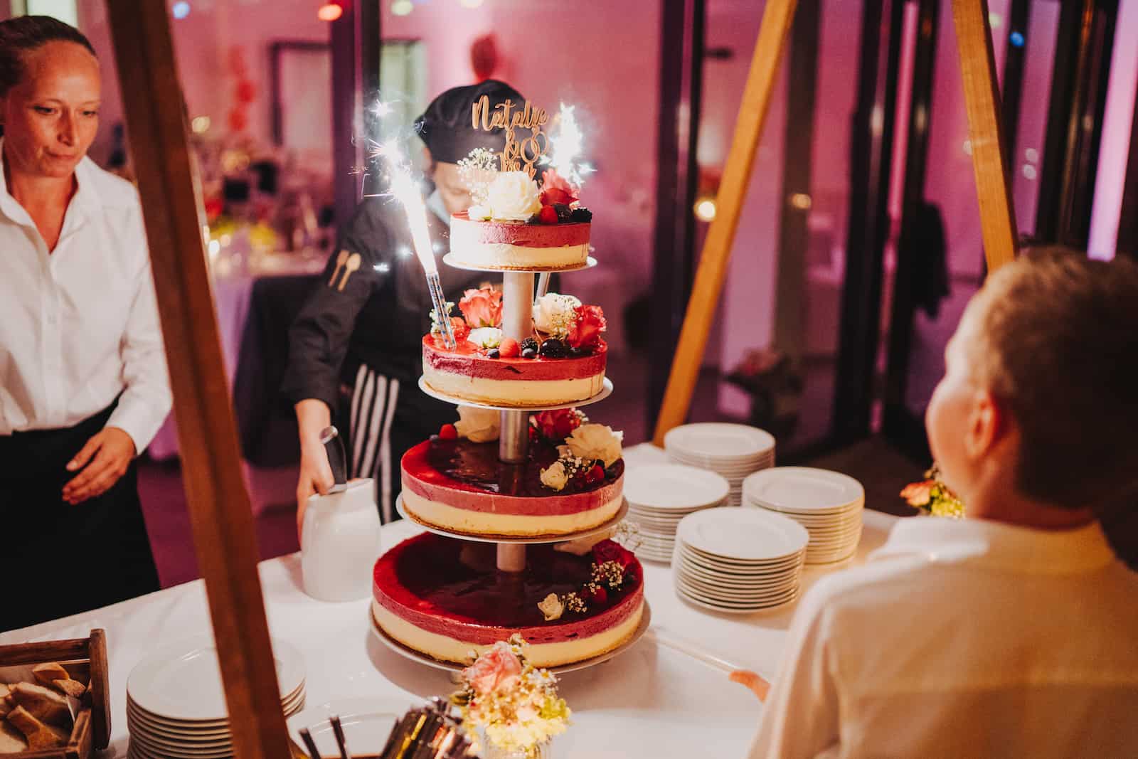 Hochzeitsfotografie in Kernen mit einer mehrstöckigen Hochzeitstorte und funkelnden Kerzen, festgehalten vom Hochzeitsfotografen Niklas Hesser.