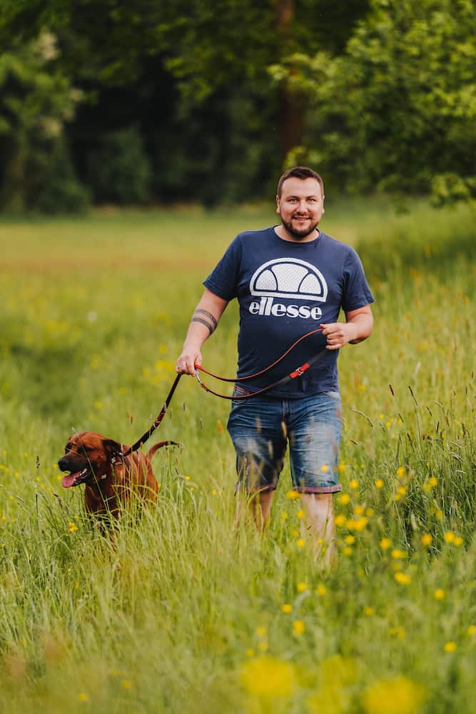 Mann mit Hund beim Spaziergang in einer grünen Wiese in Möckmühl, aufgenommen vom Eventfotografen Niklas Hesser.