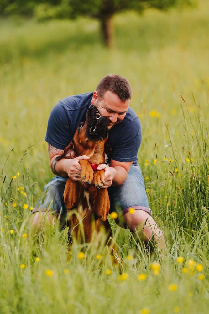 Mann spielt mit Hund auf einer Wiese in Möckmühl, aufgenommen vom Eventfotografen Niklas Hesser