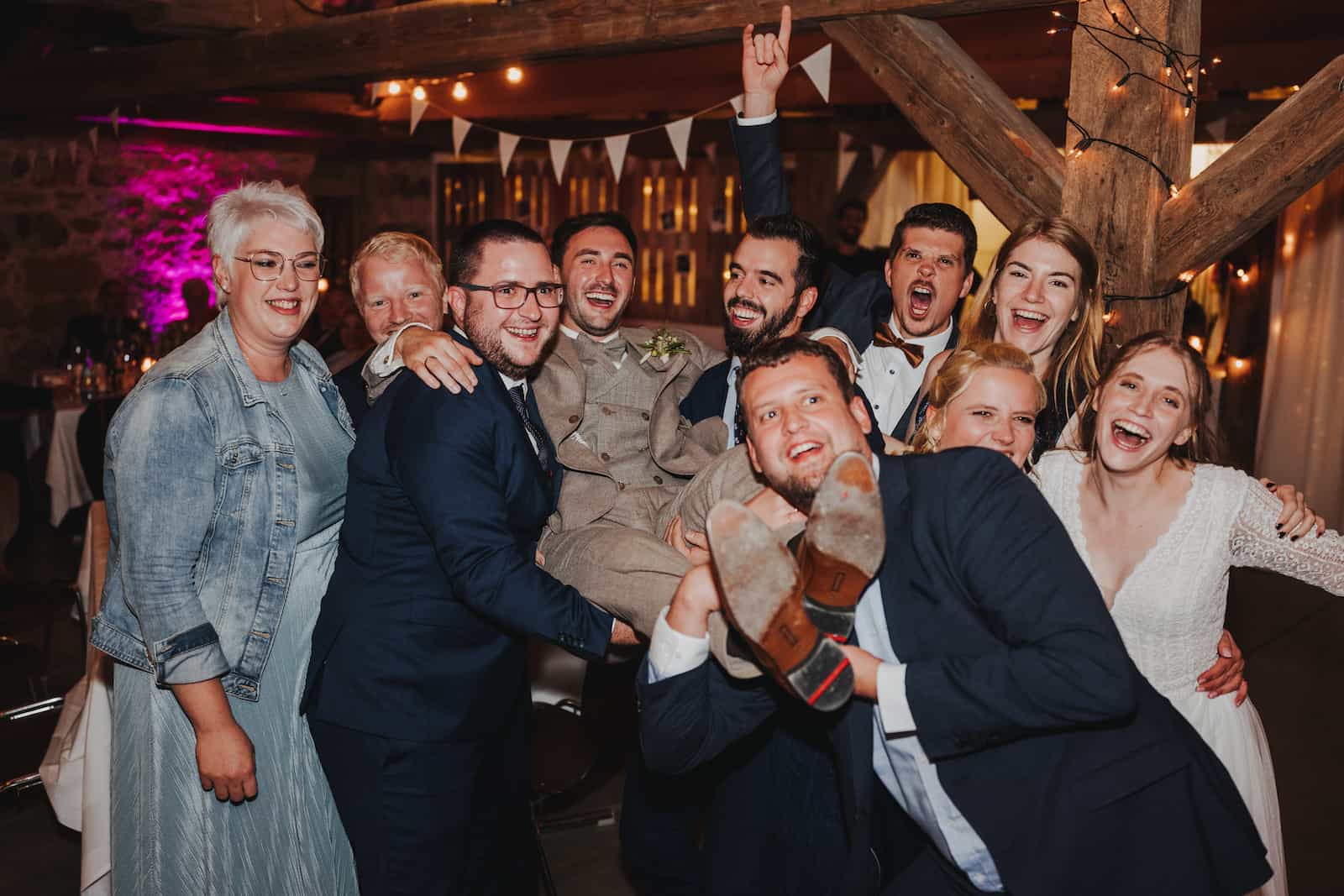 Hochzeitsfeier in Langenbeutingen, festgehalten vom Hochzeitsfotografen Niklas Hesser, zeigt fröhliche Gäste, die den Bräutigam hochheben.