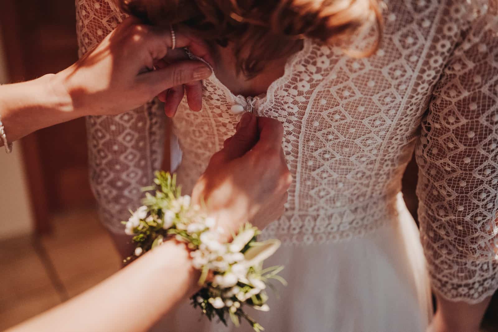 Detailaufnahme einer Braut, die ihr Hochzeitskleid im Standesamt in Langenbeutingen anlegt, fotografiert vom Hochzeitsfotografen Niklas Hesser.