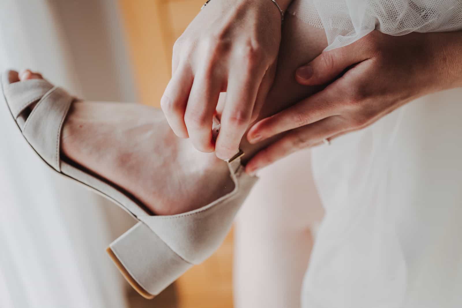 Detailaufnahme einer Braut, die ihren Schuh anzieht, festgehalten vom Hochzeitsfotografen in Langenbeutingen.