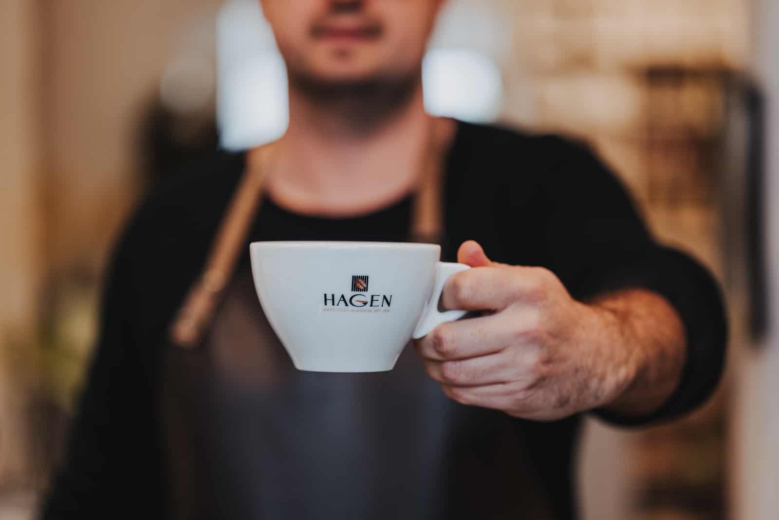 Unternehmensreportage in Heilbronn mit Fokus auf Barista, der eine Tasse Kaffee präsentiert