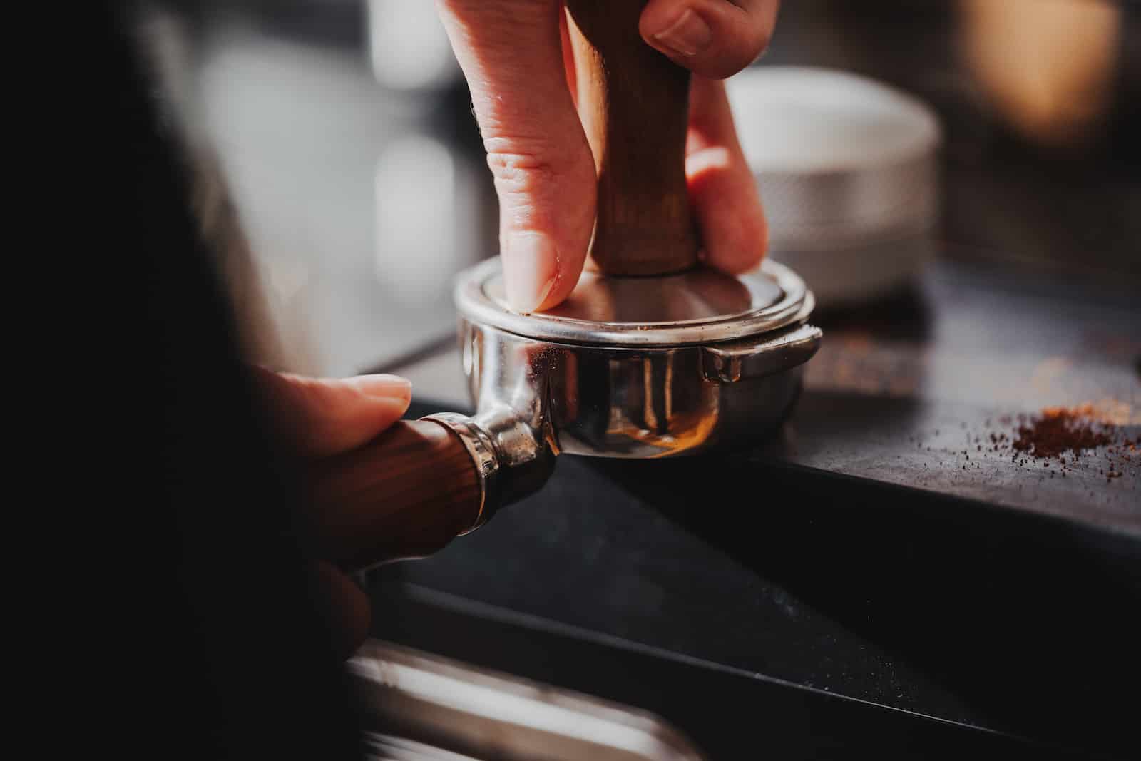 Detailaufnahme eines Baristas, der Kaffee in einem Siebträger für eine Unternehmensreportage in Heilbronn vorbereitet.