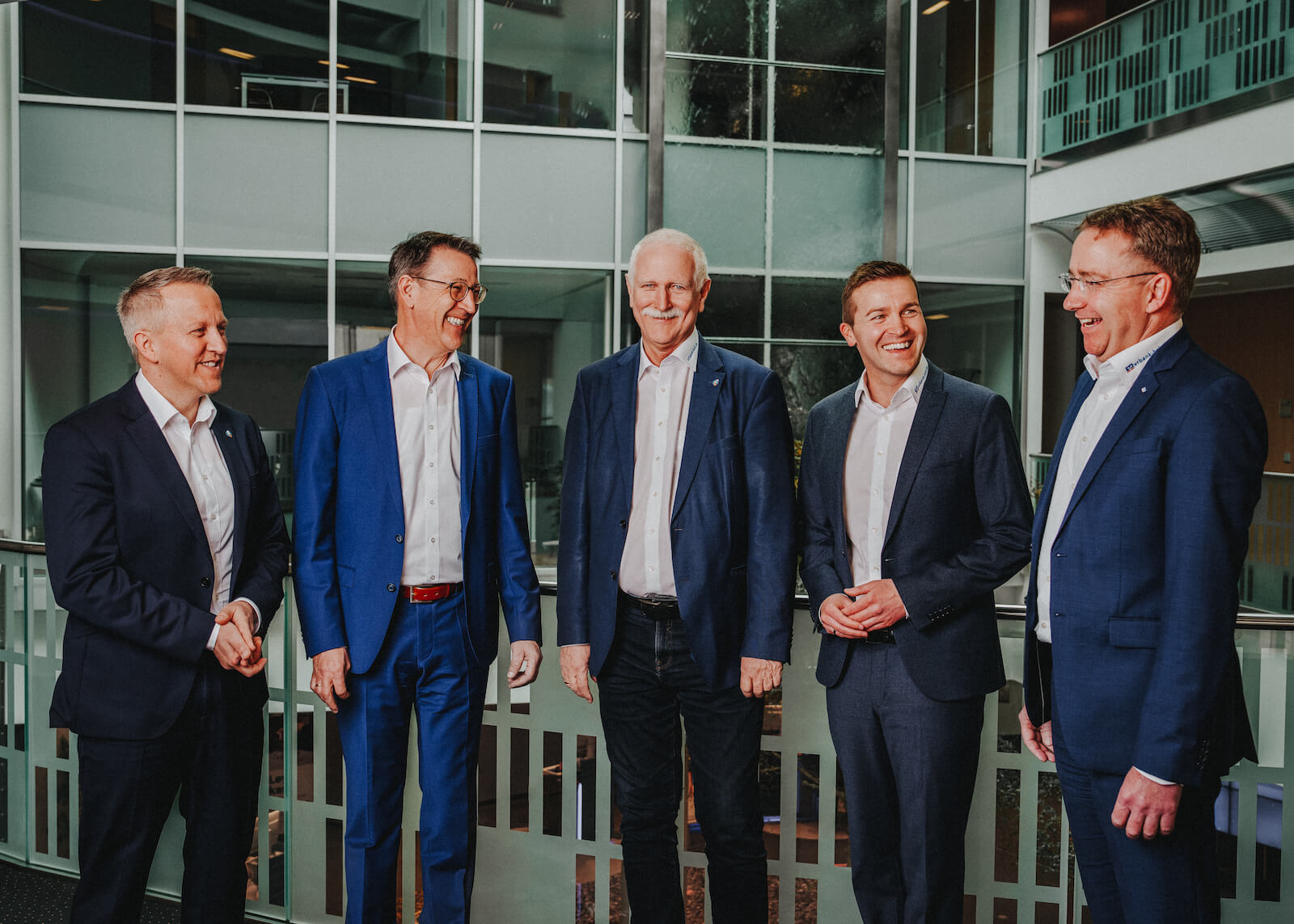 Businessportraits in Schwäbisch Hall von Niklas Hesser, fünf Männer in Anzügen lächelnd in einem modernen Bürogebäude