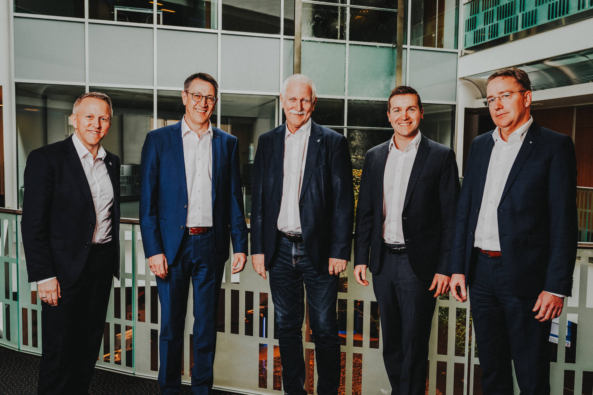 Businessportraits von fünf Männern in Anzügen in einem modernen Bürogebäude in Schwäbisch Hall, aufgenommen vom Eventfotografen Niklas Hesser.