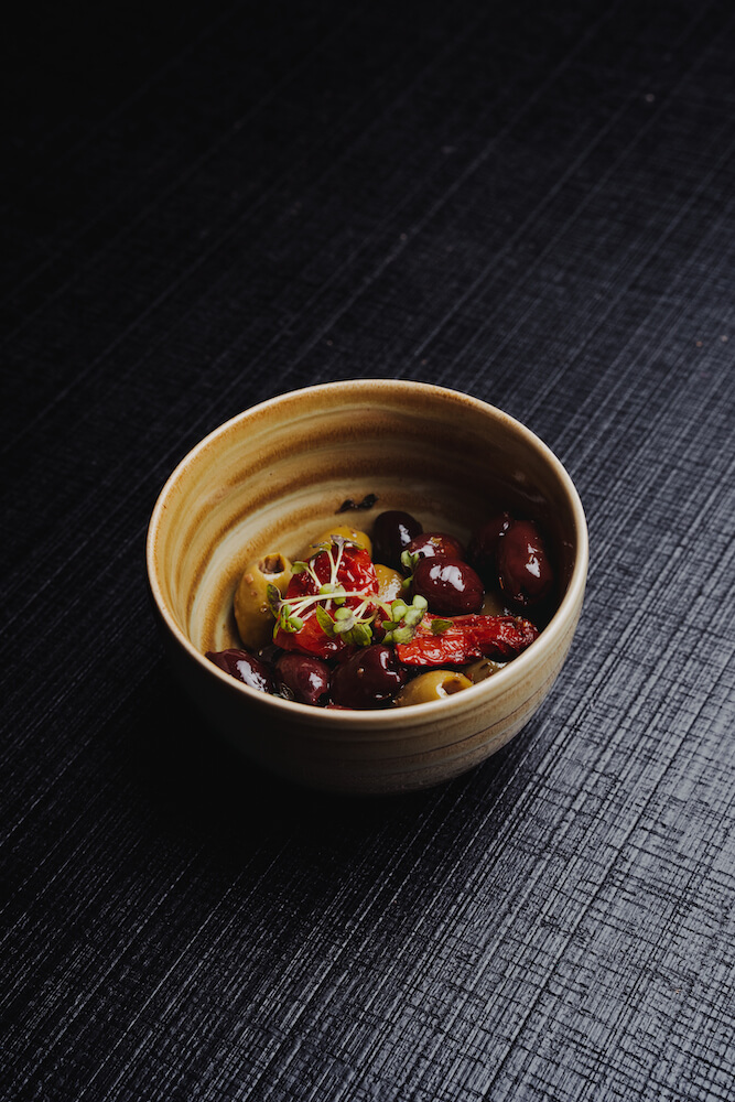 Food-Fotografie einer Schale mit Oliven und getrockneten Tomaten auf dunklem Hintergrund, aufgenommen vom Eventfotografen Niklas Hesser in Heilbronn.