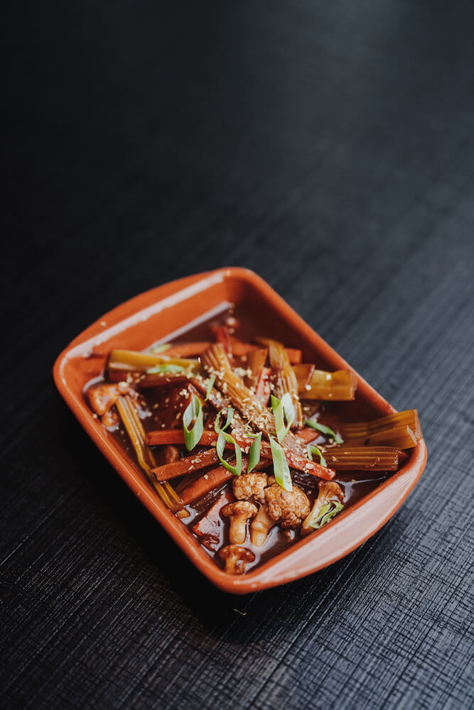 Food-Fotografie eines asiatischen Gerichts in einer braunen Schale auf dunklem Hintergrund