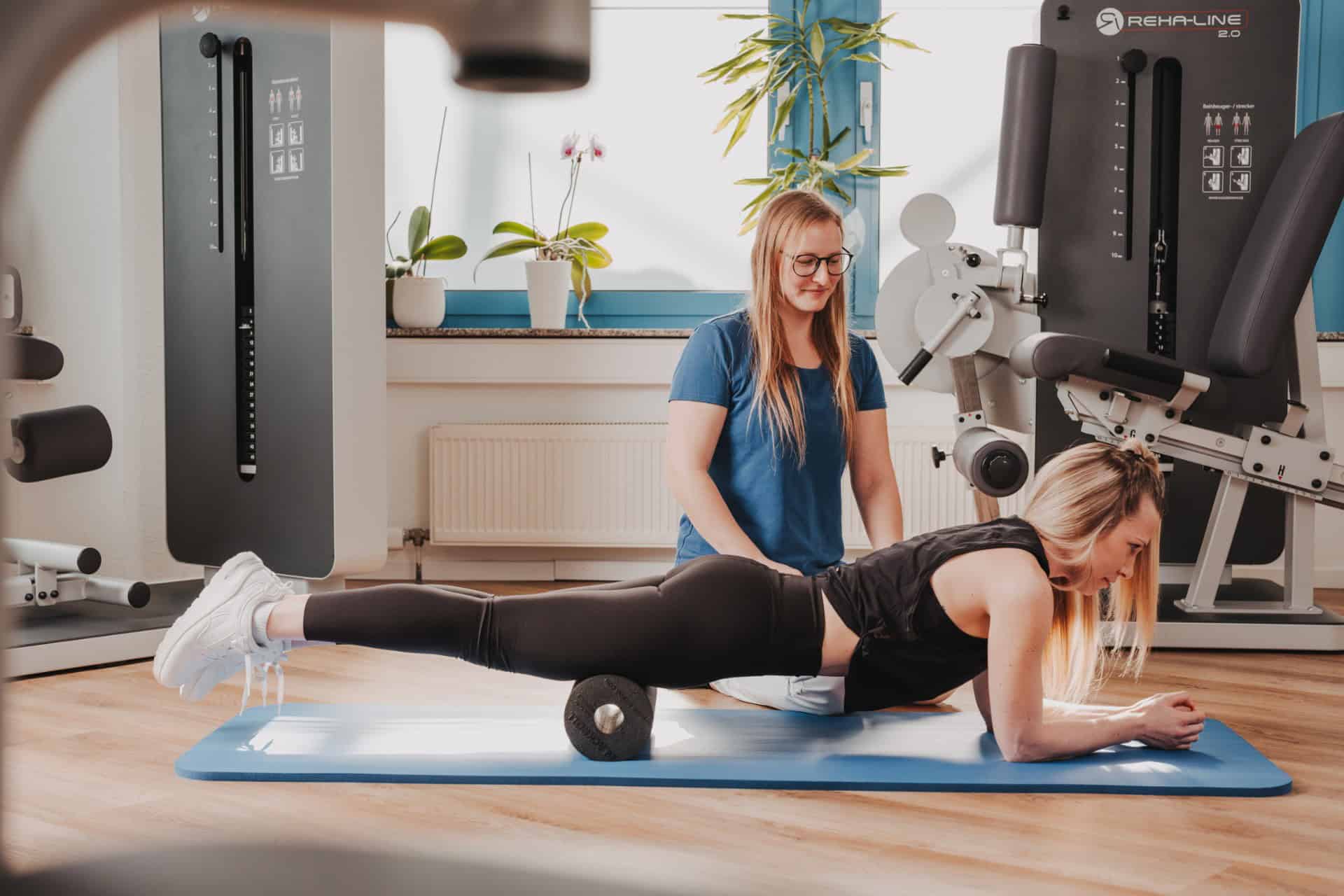 Physiotherapeutin von PhysioLogisch Erlenbach betreut Patientin in Bauchlage beim gezielten Faszienrollen im Hüftbereich