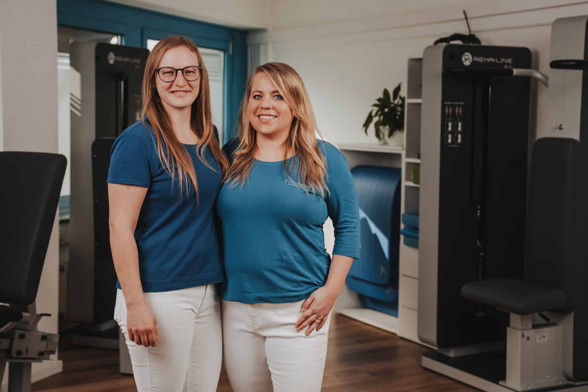 Teamportrait der Physiotherapeutinnen Grötzinger und Schmückle von PhysioLogisch Erlenbach vor modernen Reha-Geräten