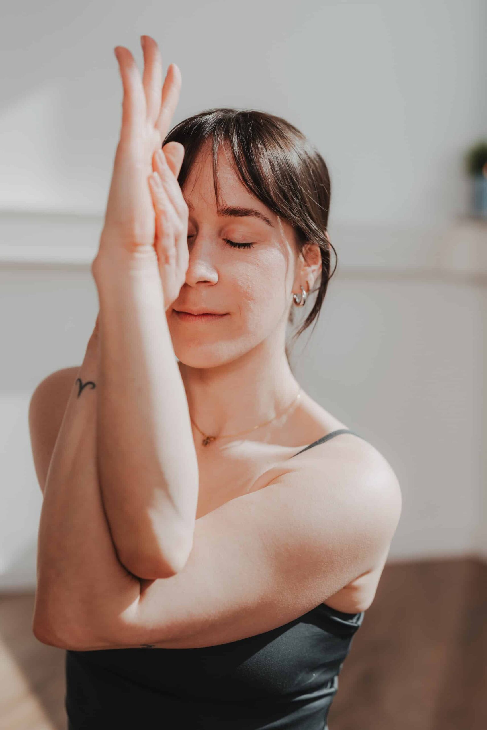 Yoga-Kursleiterin von PhysioLogisch Erlenbach im meditativen Portrait mit Anjali Mudra – Hände gefaltet vor dem Gesicht, Augen geschlossen